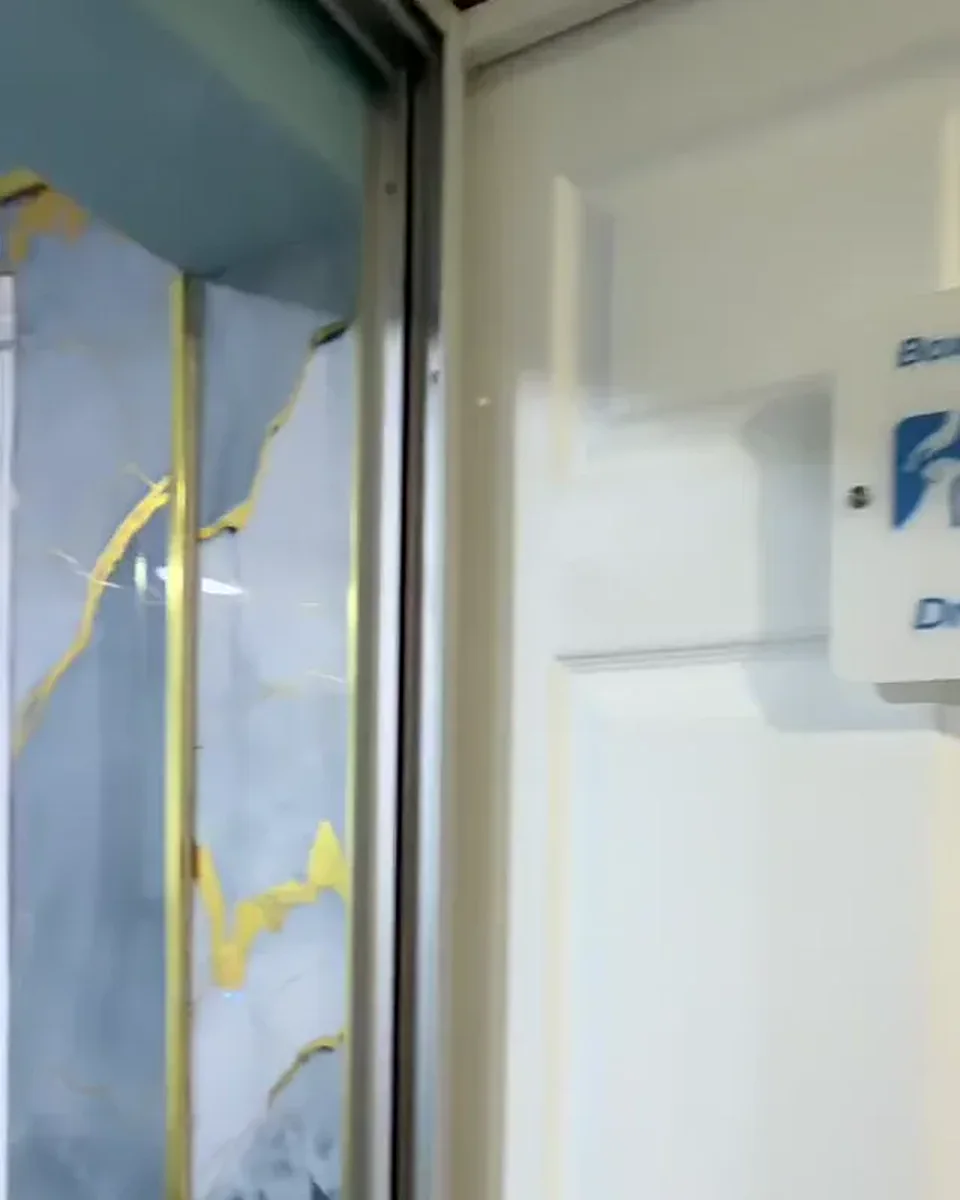 Puerta blanca de un box de especialidad con su letrero, junto a la pared de mármol