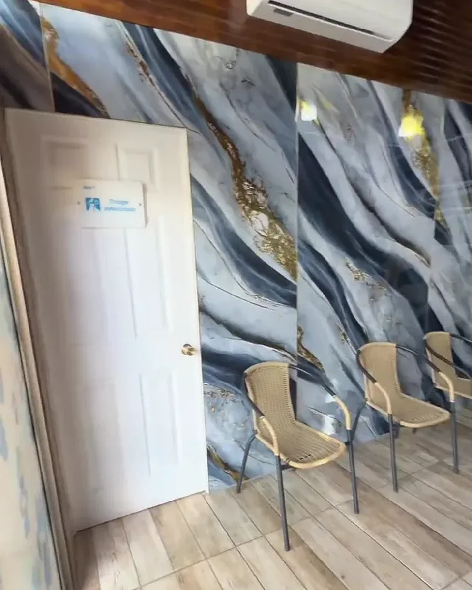 Tres sillas de mimbre junto a la pared de mármol azul de la sala de espera